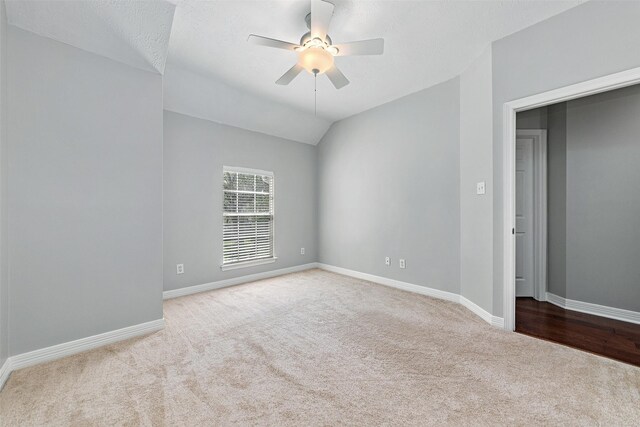 unfurnished room featuring ceiling fan, light colored carpet, vaulted ceiling, and a textured ceiling