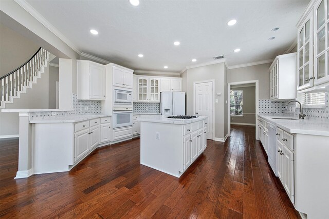 kitchen with a center island, white appliances, dark hardwood / wood-style flooring, white cabinets, and sink