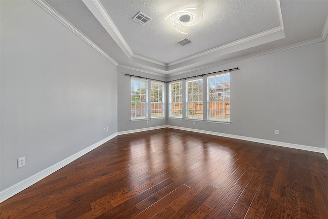 empty room featuring a textured ceiling, dark wood-type flooring, crown molding, and a raised ceiling