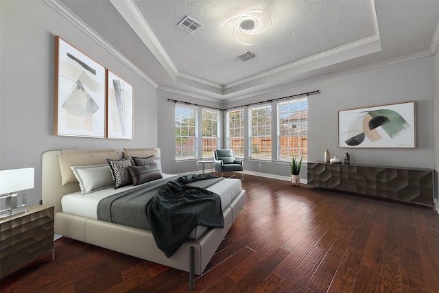 bedroom with a textured ceiling, dark wood-type flooring, crown molding, and a tray ceiling