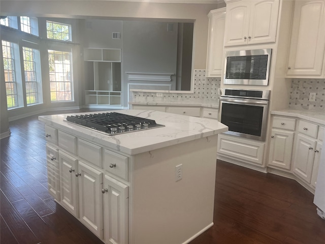 kitchen featuring light stone countertops, white cabinets, a center island, dark hardwood / wood-style flooring, and stainless steel appliances