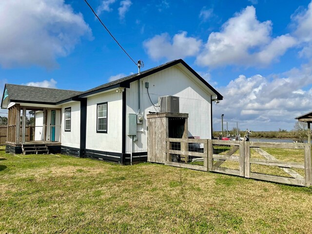 view of property exterior with roof with shingles, a lawn, fence, and central air condition unit