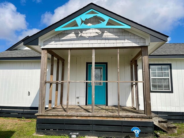 entrance to property with covered porch and roof with shingles