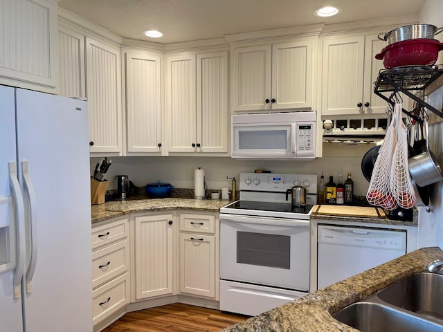 kitchen with sink, light wood-type flooring, white appliances, light stone countertops, and white cabinets