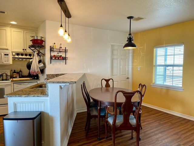 dining space featuring visible vents, baseboards, dark wood finished floors, and a textured ceiling