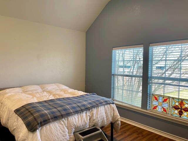 bedroom with baseboards, vaulted ceiling, and wood finished floors