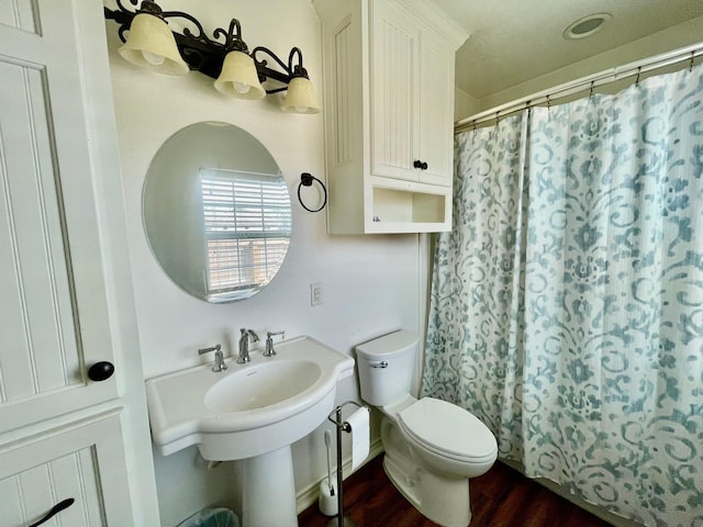 bathroom with hardwood / wood-style flooring, a shower with shower curtain, and toilet