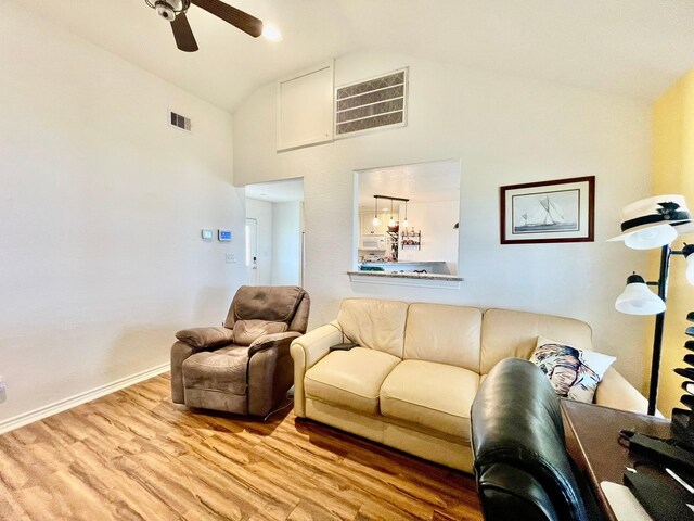 living area featuring high vaulted ceiling, visible vents, baseboards, and wood finished floors