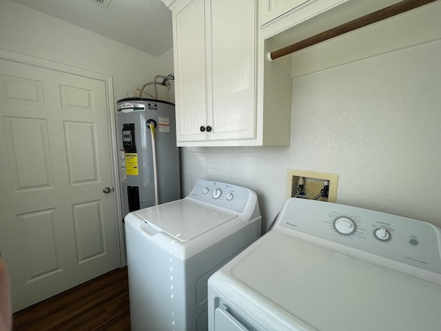 clothes washing area with cabinets, dark hardwood / wood-style floors, washer and clothes dryer, and electric water heater