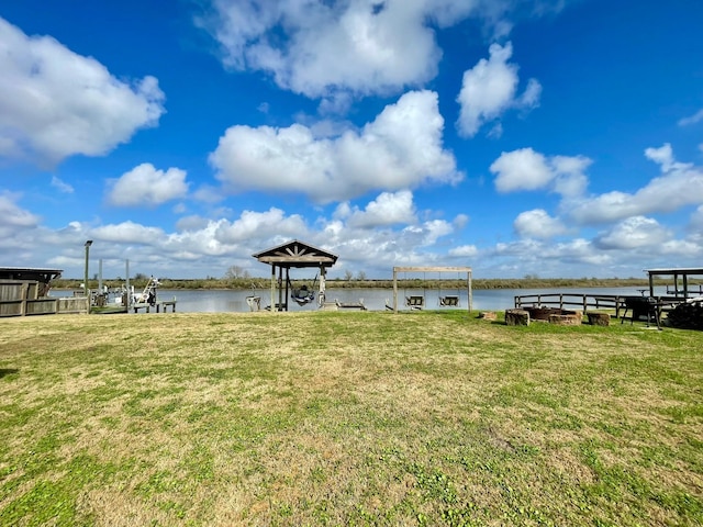 view of dock with a water view and a lawn