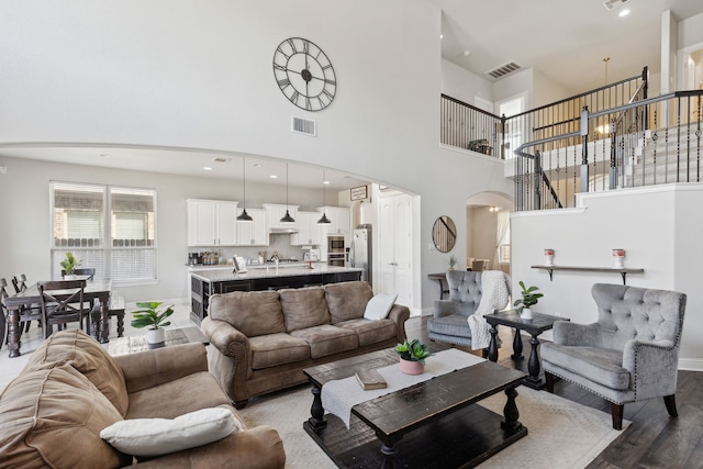 living room with a high ceiling, light hardwood / wood-style flooring, and an inviting chandelier