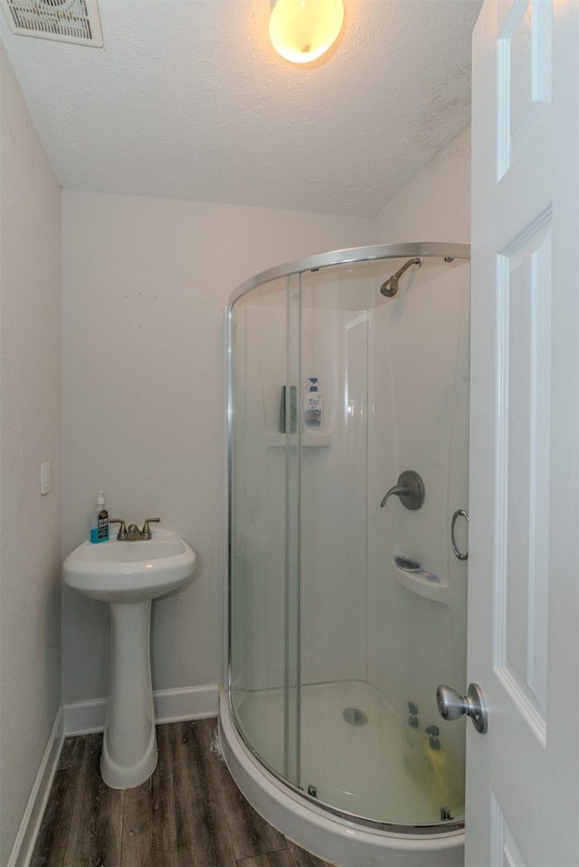 bathroom featuring hardwood / wood-style floors, a textured ceiling, and an enclosed shower