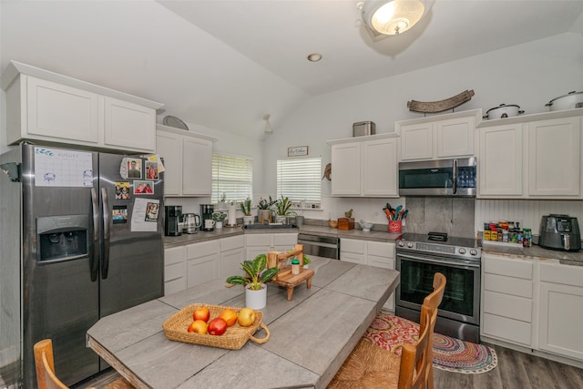 kitchen featuring vaulted ceiling, tasteful backsplash, dark wood-type flooring, stainless steel appliances, and white cabinetry