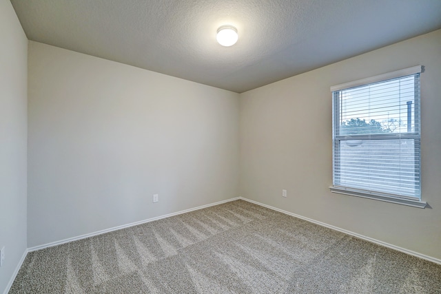 carpeted empty room featuring a textured ceiling