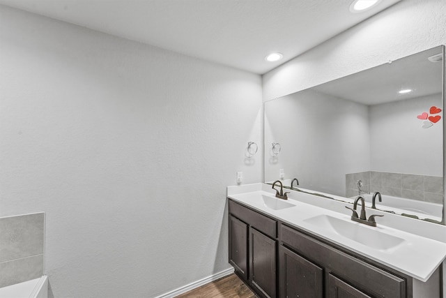 bathroom with a tub, hardwood / wood-style flooring, and vanity