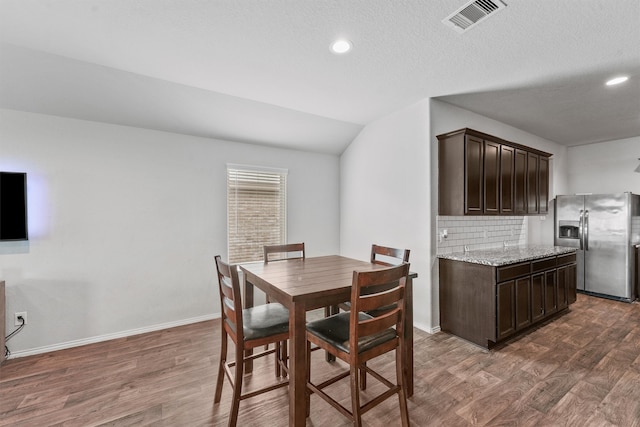 dining space featuring a textured ceiling, lofted ceiling, and dark hardwood / wood-style floors