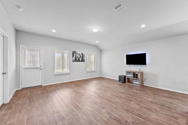 unfurnished living room featuring a textured ceiling, vaulted ceiling, and hardwood / wood-style flooring