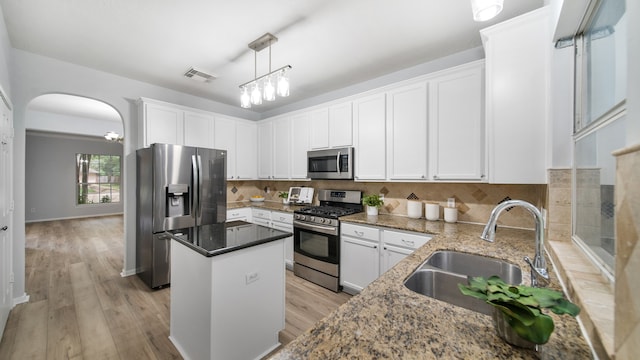 kitchen featuring appliances with stainless steel finishes, sink, a center island, light hardwood / wood-style floors, and white cabinetry