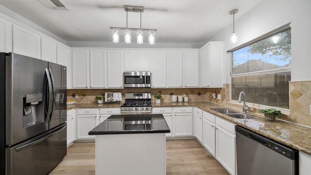 kitchen with a center island, white cabinets, sink, hanging light fixtures, and stainless steel appliances