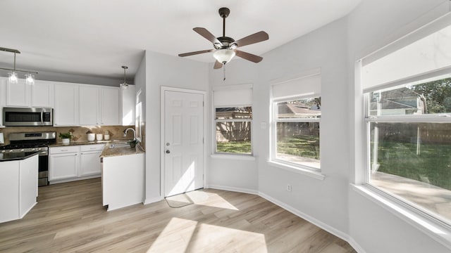 kitchen featuring white cabinets, sink, stainless steel appliances, and hanging light fixtures