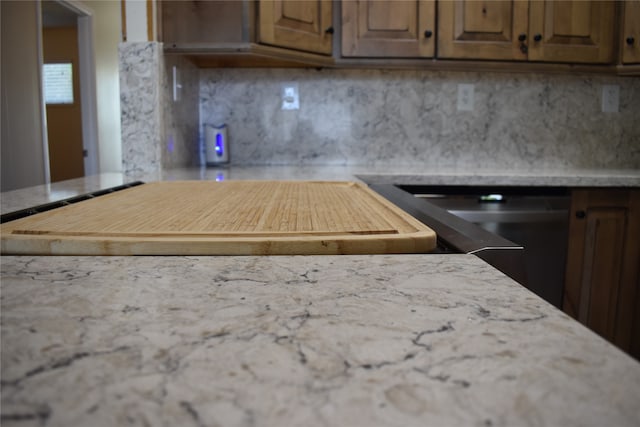 kitchen featuring black dishwasher, light stone countertops, and tasteful backsplash