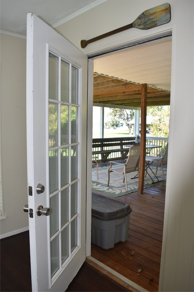 entryway with wood walls, crown molding, a healthy amount of sunlight, and dark hardwood / wood-style flooring