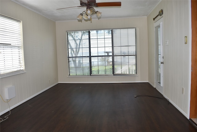 empty room featuring a wealth of natural light, ceiling fan, dark hardwood / wood-style floors, and crown molding