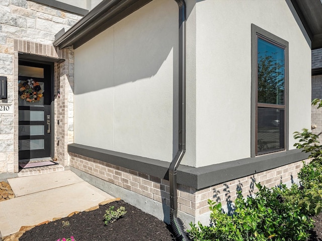 property entrance featuring brick siding and stucco siding