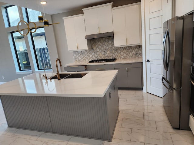 kitchen featuring white cabinets, sink, stainless steel appliances, and an island with sink