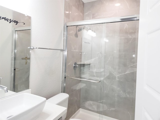 bathroom featuring sink, a shower with door, and toilet