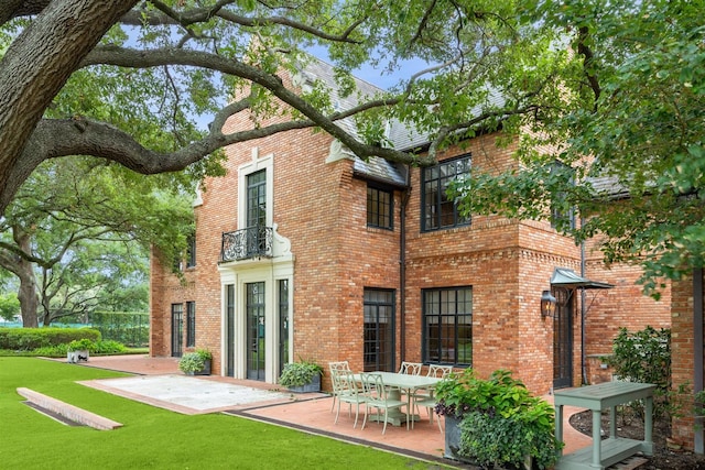 back of property with a balcony, a yard, and a patio