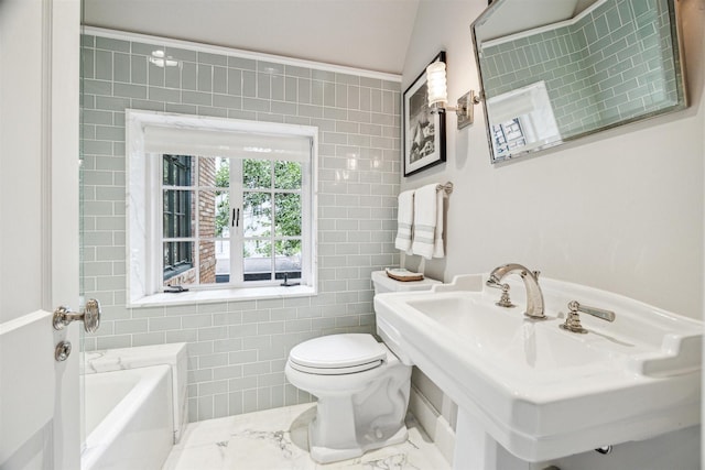 bathroom with sink, vaulted ceiling, toilet, tile walls, and a tub