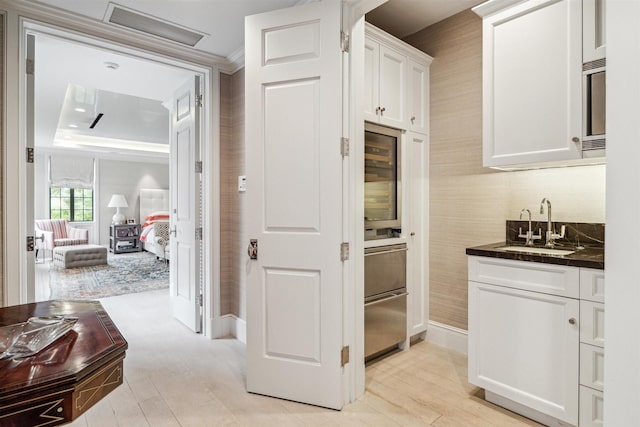 kitchen featuring white cabinets, beverage cooler, and sink