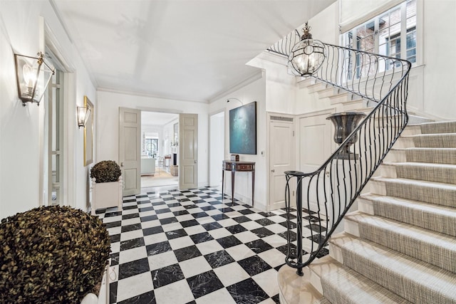 foyer entrance featuring crown molding, plenty of natural light, and an inviting chandelier