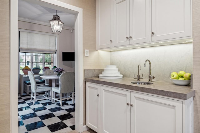 interior space featuring white cabinets, pendant lighting, crown molding, and sink