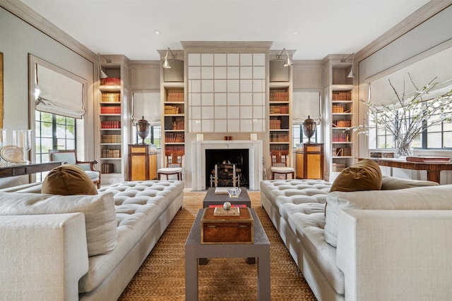 living room with built in shelves, a fireplace, and ornamental molding