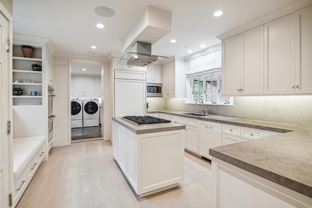 kitchen with sink, a kitchen island, separate washer and dryer, built in appliances, and white cabinets