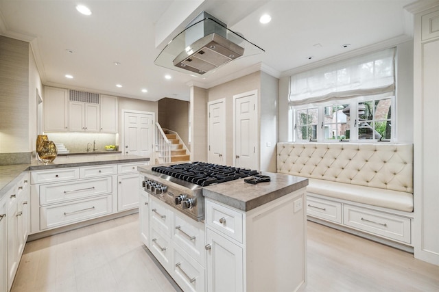 kitchen with a center island, stainless steel gas cooktop, crown molding, island range hood, and white cabinets