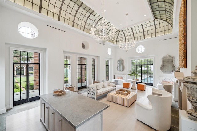 living room featuring plenty of natural light, french doors, a high ceiling, and a chandelier