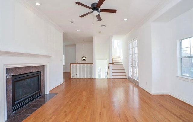 unfurnished living room featuring crown molding, ceiling fan, a tiled fireplace, and dark hardwood / wood-style floors