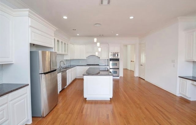 kitchen featuring light wood-type flooring, appliances with stainless steel finishes, white cabinetry, and a center island