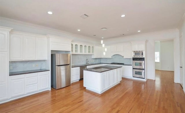 kitchen featuring white cabinets, stainless steel appliances, light hardwood / wood-style floors, and tasteful backsplash