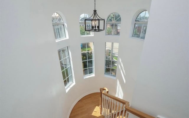 stairs with a chandelier, wood-type flooring, and a high ceiling