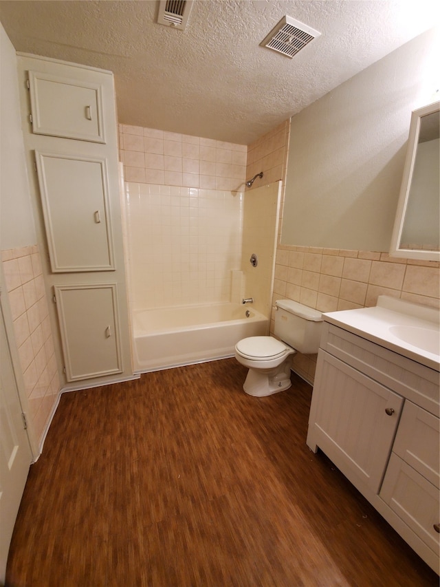 full bathroom featuring hardwood / wood-style flooring, toilet, tile walls, vanity, and a textured ceiling