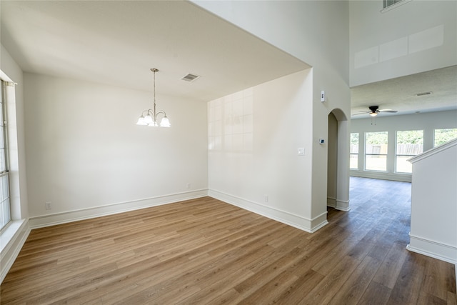 unfurnished room with ceiling fan with notable chandelier and wood-type flooring