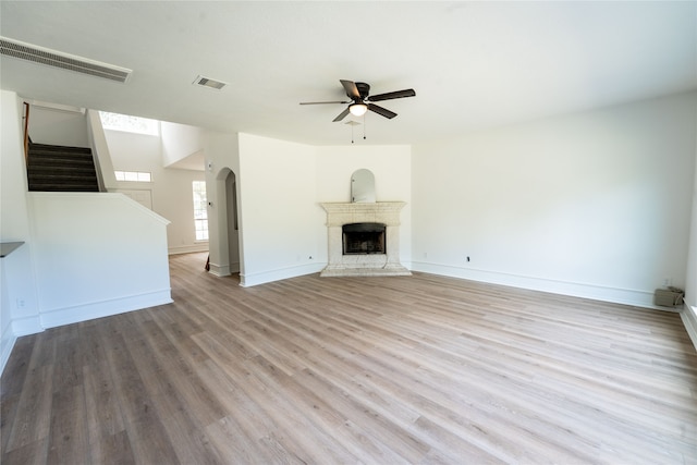 unfurnished living room featuring a fireplace, ceiling fan, and light hardwood / wood-style floors