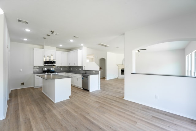 kitchen featuring light hardwood / wood-style flooring, stainless steel appliances, white cabinets, and hanging light fixtures