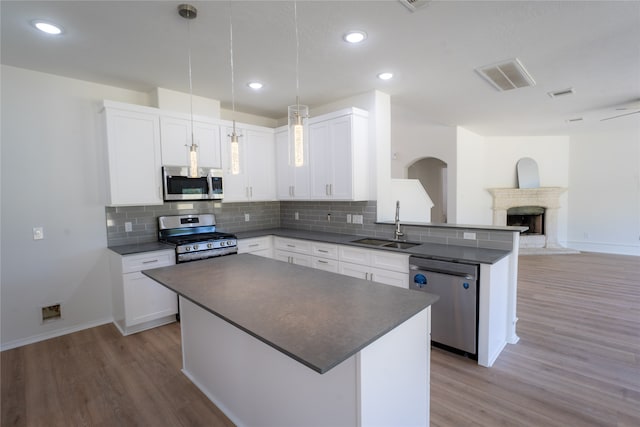 kitchen featuring white cabinetry, stainless steel appliances, a brick fireplace, sink, and light hardwood / wood-style floors