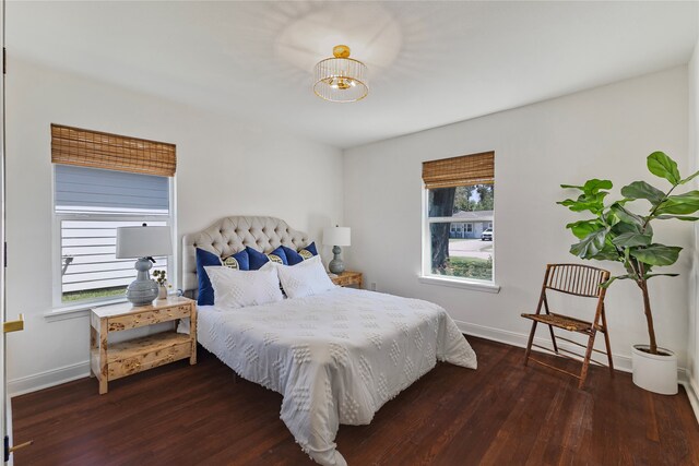 bedroom featuring dark hardwood / wood-style flooring, an inviting chandelier, and multiple windows