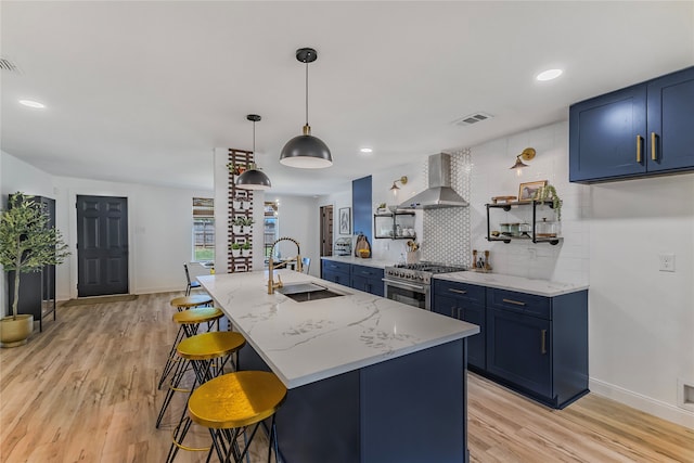 kitchen featuring blue cabinetry, high end range, light stone countertops, and wall chimney range hood